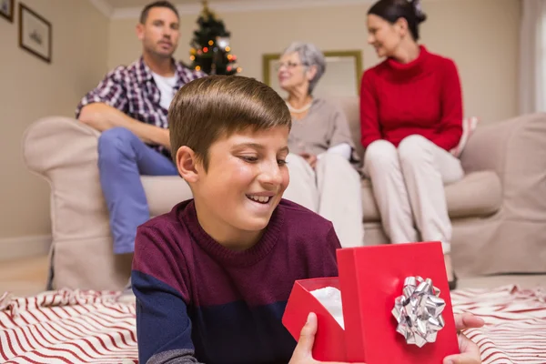 Happy son lying and opening gift — Stock Photo, Image