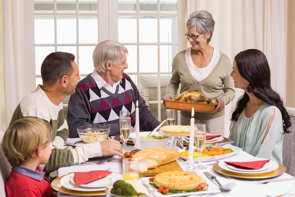 Avó segurando assado de peru com a família na mesa de jantar — Fotografia de Stock