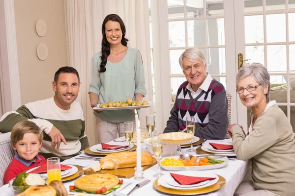 식사 테이블에 가족과 함께 크리스마스 저녁 식사를 들고 여자 — 스톡 사진