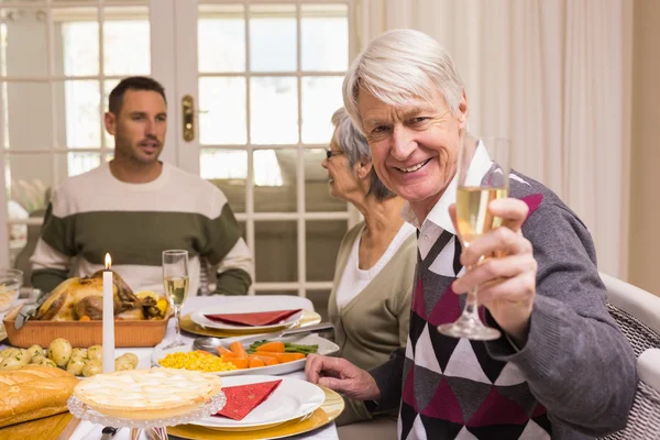 Lachende grootvader roosteren op camera voor zijn familie — Stockfoto