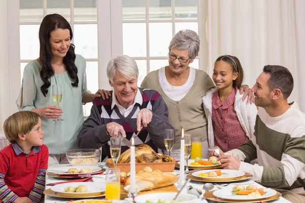 Grandfather carving chicken and his family looking him — Stock Photo, Image