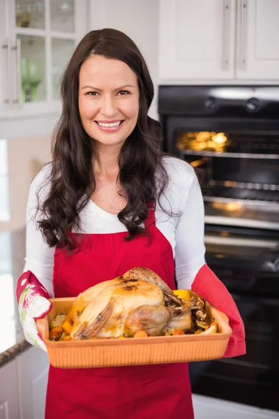 Happy brunette holding her roast turkey — Stock Photo, Image