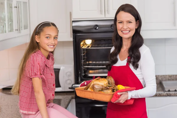 Happy mother and daughter posing with roast turkey — Stock Photo, Image