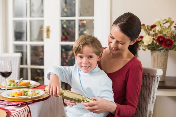 Pequeño niño tirando de una galleta de Navidad con su madre — Foto de Stock