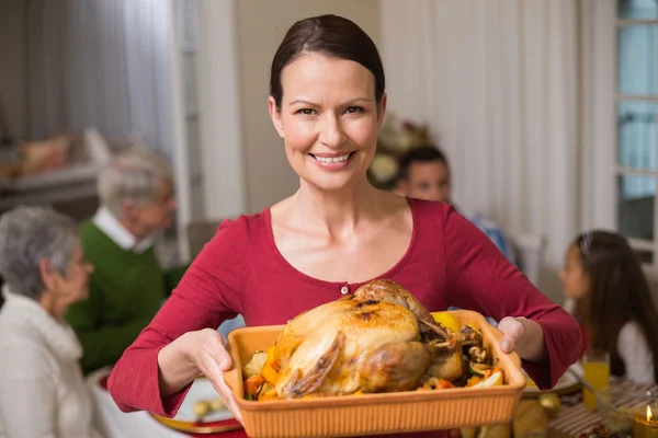 Jolie femme montrant la dinde rôtie devant sa famille — Photo