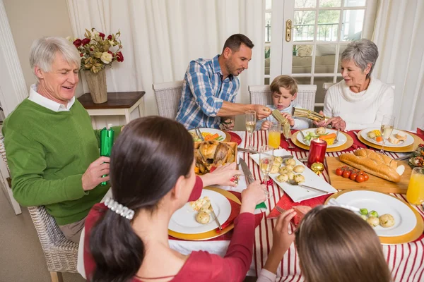 Улыбающаяся семья тянет рождественские крекеры за обеденный стол — стоковое фото