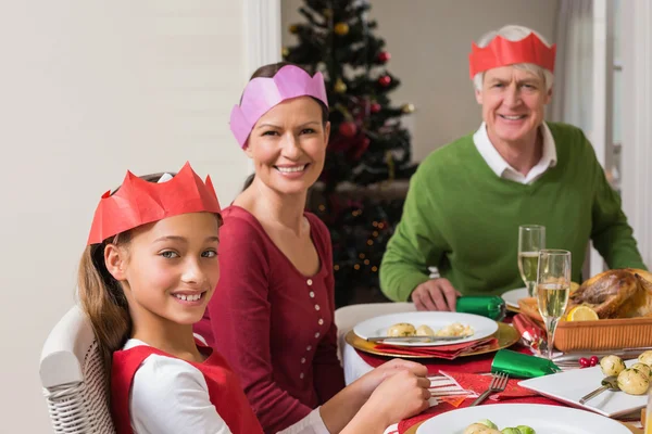 Uitgebreide familie in feest hoed aan diner tafel glimlachen — Stockfoto