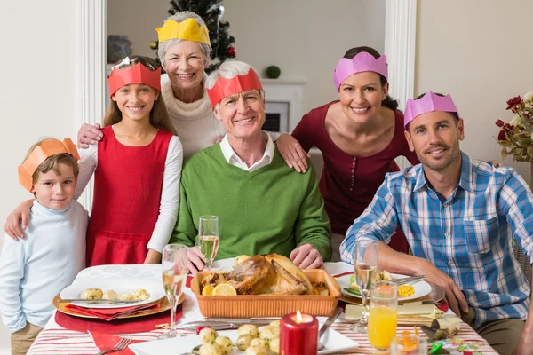 Gelukkig familie in feest hoed aan diner tafel — Stockfoto