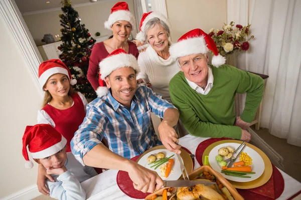 Far i santa hatt carving kyckling på julbord — Stockfoto