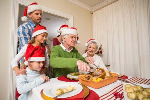 Grand-père dans le chapeau de père Noël sculptant le poulet à Noël — Photo