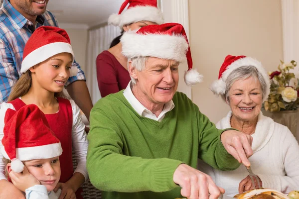 Nonno in cappello di Babbo Natale intaglio pollo a cena di Natale — Foto Stock