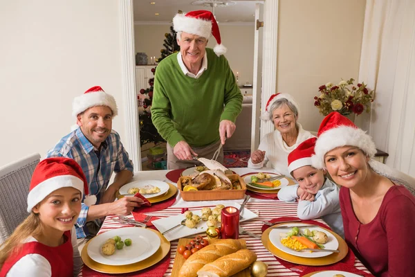 Grandfather in santa hat carving roast turkey at christmas dinne — Stock Photo, Image