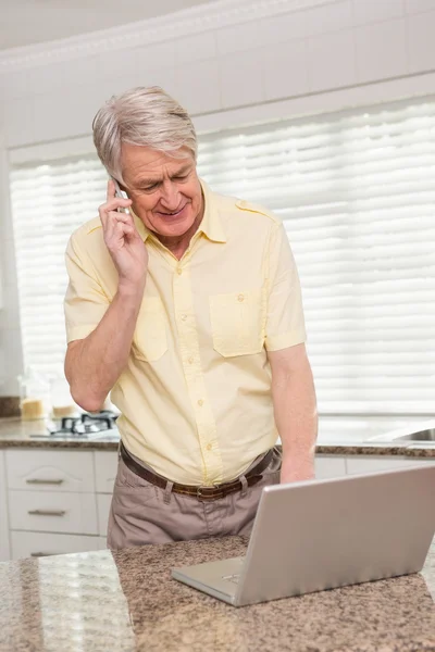 老人在电话上使用他的笔记本电脑 — 图库照片