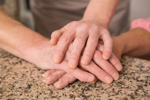 Senior paar bedrijf handen op tafel — Stockfoto