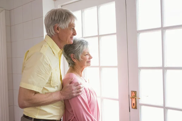 Senior paar kijkt uit hun raam — Stockfoto