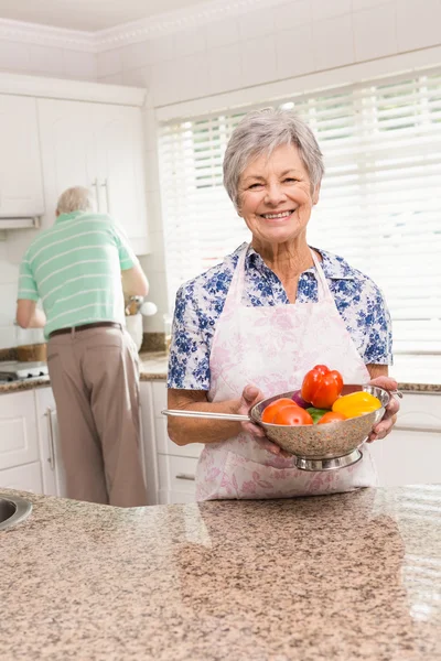 Senior woman showing colander of vegetables — Stock Photo, Image
