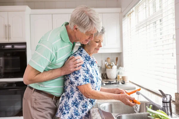 Senior couple washing vegetables at sink — Stock Photo, Image