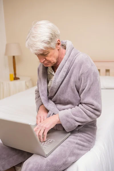 Starszy człowiek korzysta z laptopa na łóżku — Zdjęcie stockowe