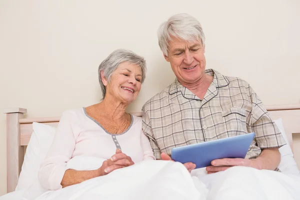 Couple sénior se détendre au lit en utilisant la tablette pc — Photo