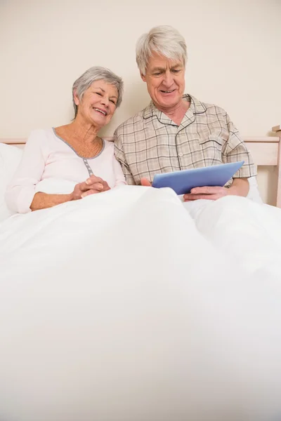 Pareja mayor relajarse en la cama con la tableta de PC — Foto de Stock