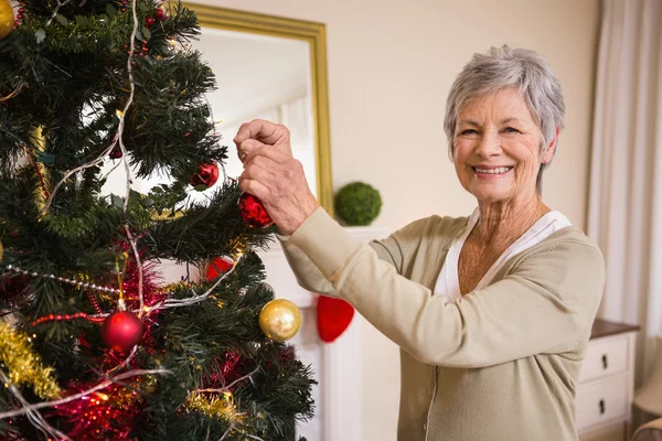 Äldre kvinna dekorera julgranen — Stockfoto