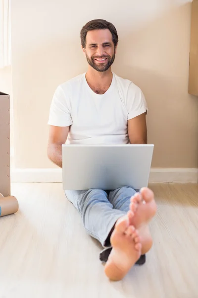 Hombre feliz usando el ordenador portátil rodeado de cajas — Foto de Stock