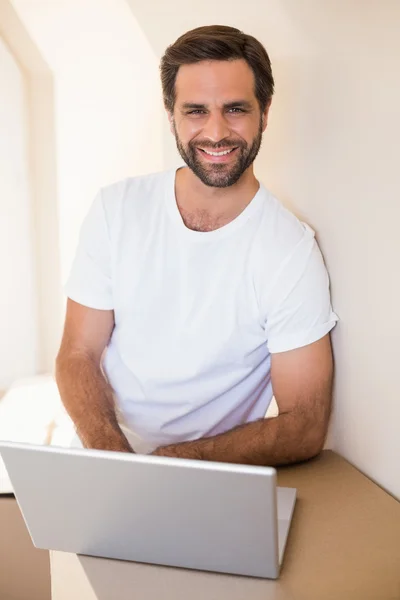Happy man using laptop after moving in — Stock Photo, Image