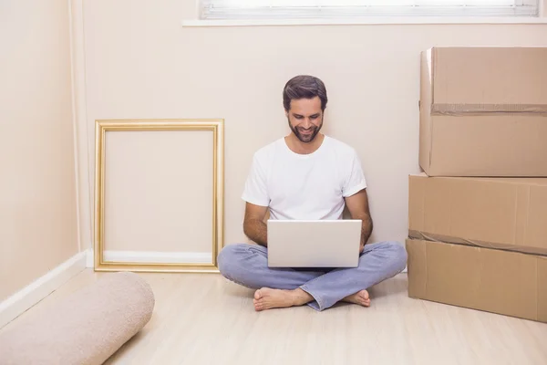 Hombre feliz usando el ordenador portátil rodeado de cajas — Foto de Stock