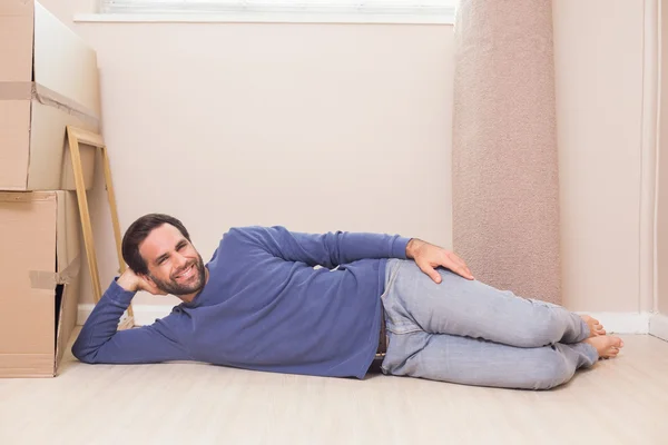 Glücklicher Mann liegt mit Umzugskartons auf dem Boden — Stockfoto