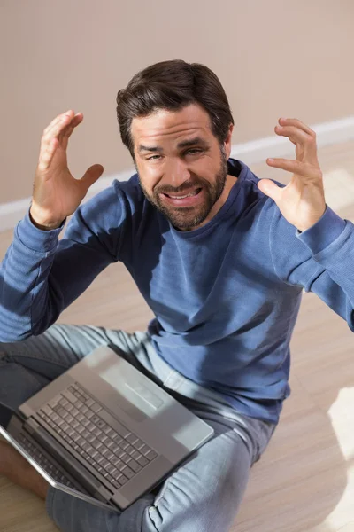 Strssed man sitting on floor using laptop — Stock Photo, Image