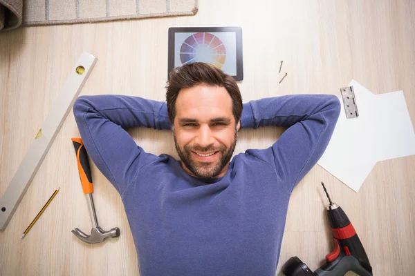 Casual man lying on floor surrounded by his diy tools — Stock Photo, Image