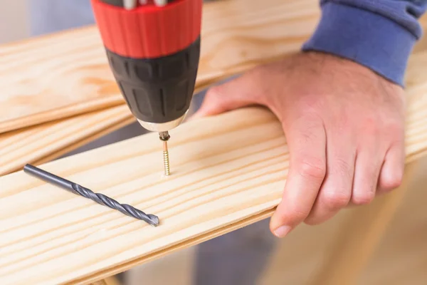 Casual man drilling hole in plank — Stock Photo, Image