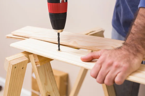 Casual man drilling hole in plank — Stock Photo, Image