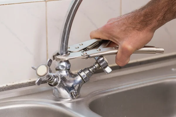 Mann fixiert Wasserhahn mit Zange — Stockfoto