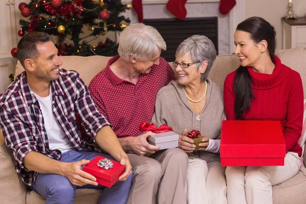 Família feliz com presente no sofá — Fotografia de Stock