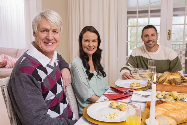 Família alegre olhando para a câmera durante o jantar de Natal — Fotografia de Stock