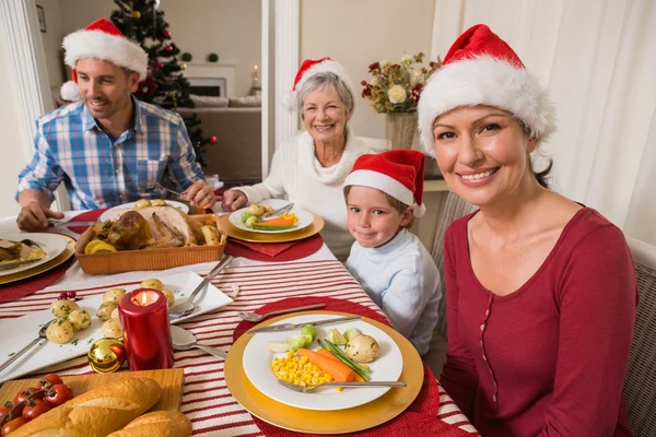 Счастливая семья в шляпе Санты во время рождественского ужина — стоковое фото