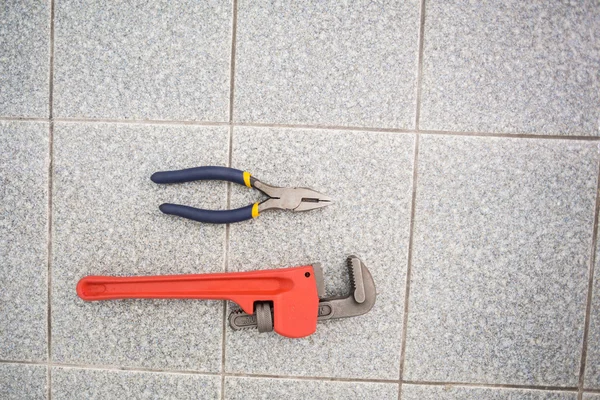 Llave y alicates en el suelo del baño — Foto de Stock