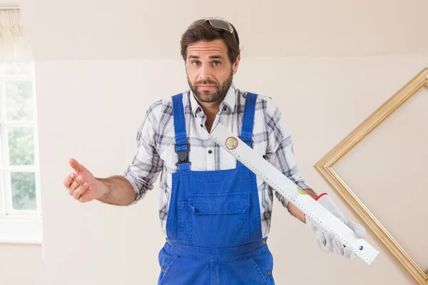 Verwirrter Bauarbeiter mit Wasserwaage — Stockfoto