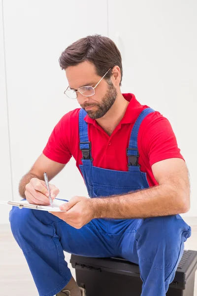 Bouwvakker maken van notities op Klembord — Stockfoto