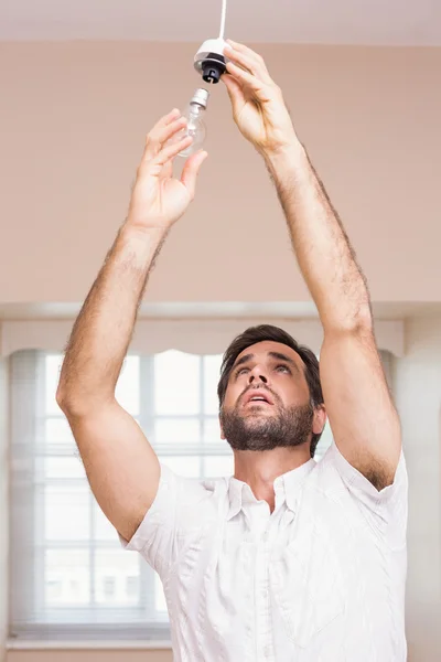 Mann ersetzt die Glühbirne — Stockfoto