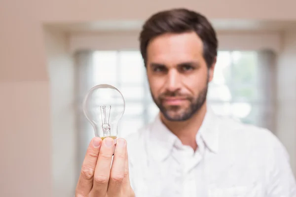 Man showing light bulb to camera — Stock Photo, Image