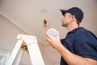 Handyman installing smoke detector clipart