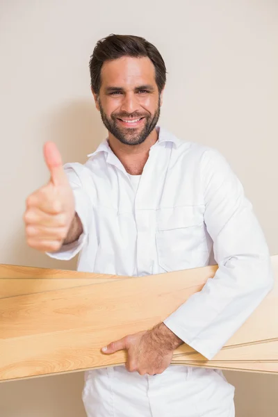 Carpenter holding planks showing thumbs up — Stock Photo, Image