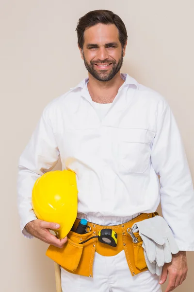 Handyman sosteniendo su casco amarillo en el cinturón de herramientas —  Fotos de Stock