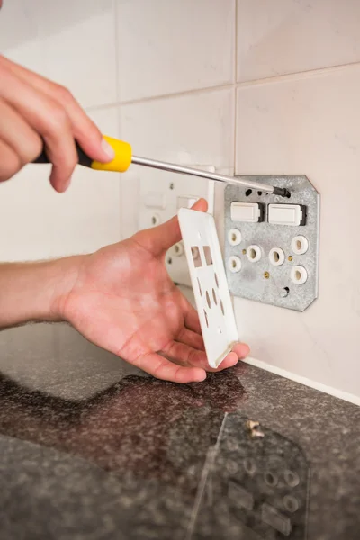 Electrician unscrewing face plate of plug socket — Stock Photo, Image