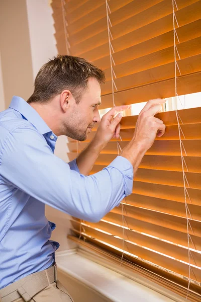 Nieuwsgierig man die via de blinds — Stockfoto