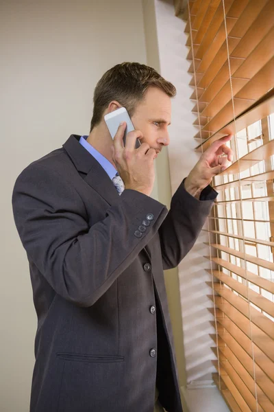 Businessman peeking through blinds — Stock Photo, Image