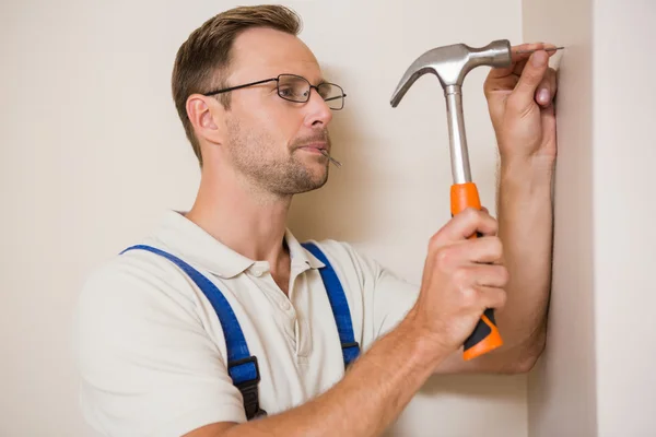 Handyman hamrande spik i väggen — Stockfoto