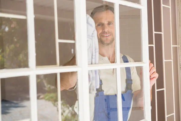 Handyman limpar a janela e sorrindo — Fotografia de Stock